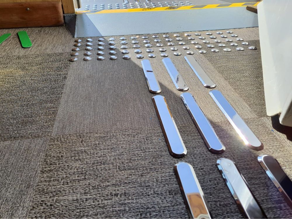 Piso tátil inox em ambiente interno, mostrando elementos direcionais e de alerta para ilustrar para que serve o piso tátil em áreas de circulação segura.
