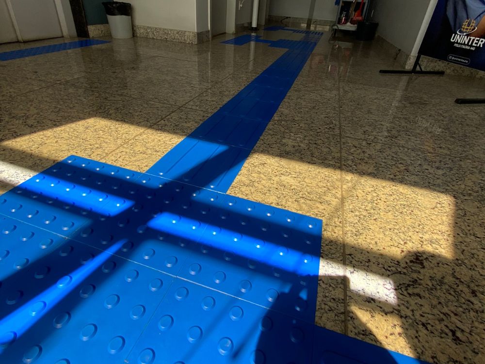 Piso com sinalização tátil azul em ambiente interno, destacando contraste visual e aplicação prática da cor do piso tátil para acessibilidade