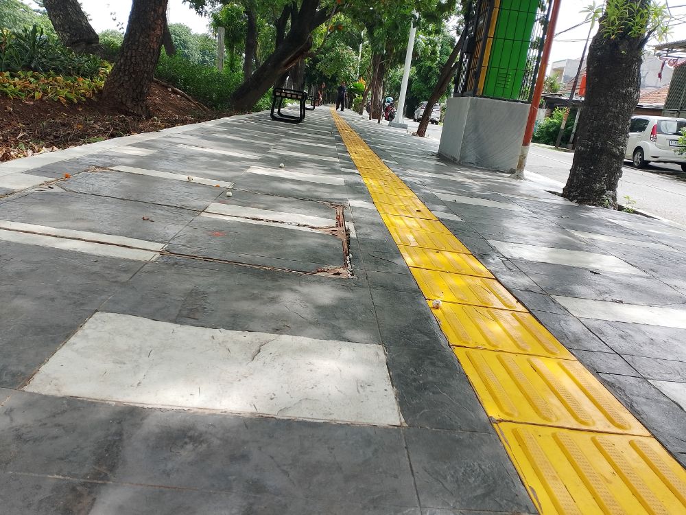 Calçada com piso tátil amarelo instalado, evidenciando como a ausência desse recurso pode gerar consequências da falta de acessibilidade para deficientes em espaços urbanos.